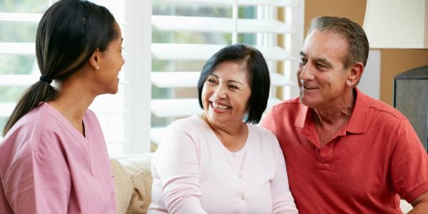 Nurse Making Notes During Home Visit With Senior Couple