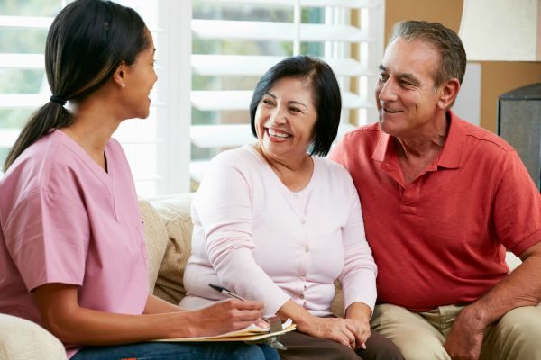 Nurse Making Notes During Home Visit With Senior Couple Nurse Making Notes During Home Visit With Senior Couple