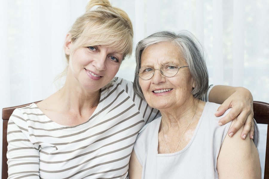 Beautiful mature daughter hugging her senior mother.